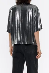 Camiseta plateada metalizada de corte recto, con escote redondo con abertura en forma de lágrima en el delantero, manga corta amplia y hombreras con pliegues.