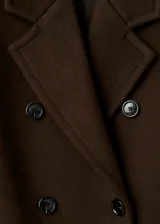 Abrigo largo de corte recto, color verde militar, confeccionado en mezcla de lana. Cuenta con cuello de solapa con muesca, cierre cruzado de doble botonadura y bolsillos con solapa en la parte frontal.
