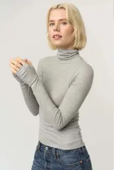 Remera de punto acanalado color gris, con cuello alto plegable y mangas largas con abertura para el pulgar en los puños.