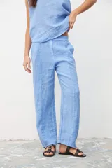 Pantalón de corte recto y tiro medio, confeccionado en lino color celeste. Presenta costuras verticales decorativas en el frente y cierre oculto.