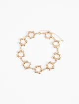 Collar choker dorado con dijes en forma de flor con centro blanco.