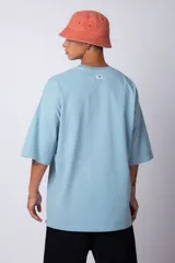 Remera de corte oversize, color blanco, con cuello redondo y mangas cortas amplias, confeccionada en algodón.