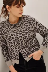 Cardigan de punto con estampado animal print en tonos gris y negro. Presenta cuello redondo con detalle de pedrería brillante, cierre frontal con botones y puños acanalados.