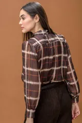 Camisa de manga larga con estampado de cuadros, cuello con lazo integrado y cierre frontal abotonado. Presenta un diseño fluido y elegante.