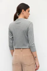 Polera de algodón color blanco, con cuello alto y mangas tres cuartos. Presenta un diseño ajustado al cuerpo con costuras decorativas en las sisas.