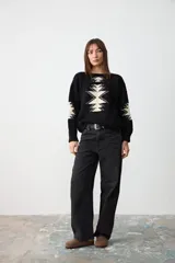 Sweater de punto negro con diseño geométrico en color crema en el frente y las mangas, de corte holgado y cuello redondo.