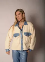 Chaqueta color crema de corderito con detalles en jean azul en cuello, solapa, bolsillos y puños.