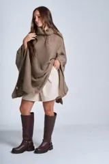 Poncho tejido color beige, con cuello alto y corte asimétrico.