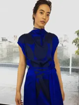 Vestido fucsia con estampado abstracto en tonos borgoña, corte midi, sin mangas, con escote en la espalda y lazo en la cintura.