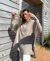 Sweater de punto color beige, con diseño oversize, cuello redondo, mangas largas con puños acanalados y tajos laterales en el ruedo.