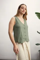 Chaleco sin mangas color verde oliva, con escote en V y cierre frontal con botones a tono. Presenta un corte entallado y ruedo asimétrico.