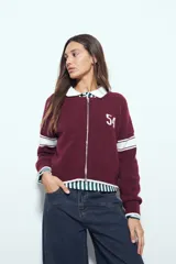 Campera de punto tipo cardigan en color bordó, con cierre frontal, cuello redondo y diseño estilo universitario. Presenta el número 54 bordado en blanco en el pecho y franjas blancas en las mangas.