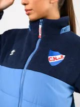Parka de abrigo Umbro del Club Nacional de Football, con diseño bicolor que combina tejido polar blanco en la parte superior y tejido acolchado azul marino en la parte inferior. Cuenta con cierre frontal completo, cuello alto y bolsillos laterales.