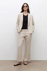 Blazer sastrero color beige melange confeccionado en lino, con solapas clásicas y cierre frontal abierto.