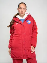 Parka larga de abrigo Umbro del Club Nacional de Football, color rojo con detalles en naranja en las mangas. Cuenta con capucha, cierre frontal con botones a presión y escudo del club bordado en el pecho.