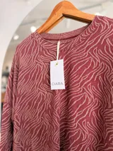 Buzo de tejido de punto con diseño de estampado tipo cebra y sutiles hilos dorados integrados. Presenta cuello redondo, mangas largas y un corte holgado.