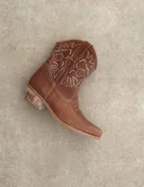 Bota corta estilo western de cuero color marrón, con taco cuadrado de 5 cm y diseño clásico. Presenta un acabado desgastado en la puntera y el talón.