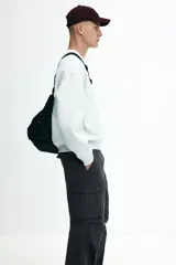 Pantalón cargo gris oscuro de corte holgado, con cintura elástica y bolsillos laterales, traseros y tipo cargo con solapa y botón a presión.