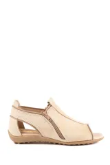 Sandalia de cuero color beige, estilo botineta abierta, con cierres laterales y suela plana texturizada.