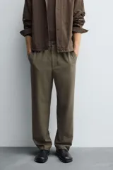 Pantalón regular fit color marrón oscuro, confeccionado en tejido con viscosa. Cuenta con cintura elástica, bolsillos delanteros y detalle de bolsillos traseros de vivo. El cierre frontal es con cremallera y botón.