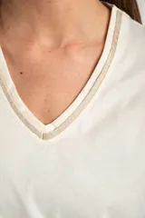 Remera de algodón peinado color blanco, con escote en V y detalles de lurex dorado en el borde del escote. De manga corta y corte ajustado.