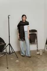 Bufanda larga tejida a crochet color negro con diseño de pequeños cuadrados blancos, rojos y azules. Termina en flecos cortos.