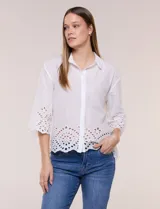 Camisa de calce holgado color blanco, confeccionada en tejido liviano de algodón, con cuello camisero clásico, mangas tres cuartos y terminación en puños y ruedo con diseño de bordado broderie calado y festoneado.