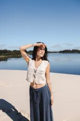 Chaleco corto tejido a crochet color crudo, sin mangas y con lazos en la parte delantera.