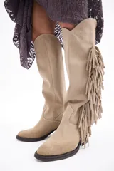 Bota bucanera de caña alta confeccionada en cuero vacuno, con diseño de estilo western que presenta flecos laterales largos y taco cuadrado.