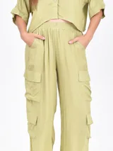 Pantalón cargo ancho de color verde oliva claro, con cintura elástica y bolsillos tipo parche a los lados de las piernas.
