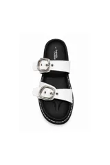Sandalias de mujer Daniel Cassin modelo Onia, de color negro con dos tiras anchas en el empeine, cada una con una hebilla metálica plateada grande. Presentan costuras blancas decorativas a lo largo de la suela y plantilla anatómica.