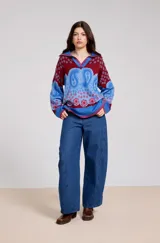 Sweater de tejido de punto con diseño estampado tipo paisley y floral en tonos azul, rojo y bordó. Presenta un cuello polo con escote en V, mangas largas y un corte holgado.