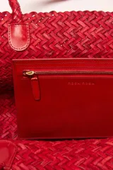 Bolso tipo tote de cuero vacuno, completamente trenzado a mano. El color es marrón oscuro, casi chocolate. Posee dos asas de hombro trenzadas.