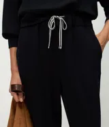 Pantalón tipo jogger de corte holgado con cintura elástica y cordón bicolor ajustable. Presenta puños elásticos en los tobillos y bolsillos laterales.