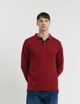 Remera de manga larga con cuello polo, confeccionada en tejido de punto canalé francés. Presenta abotonadura frontal con botones de madera y detalles a contratono en la cartera y el interior del cuello.