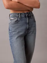 Jeans mom fit de tiro alto y pierna cónica, en denim azul con efecto deslavado. Cuenta con diseño clásico de cinco bolsillos, cierre de botón y cremallera, y detalles distintivos de la marca Calvin Klein.