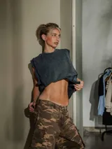 Musculosa sin mangas color gris oscuro con efecto lavado y bordes deshilachados. Presenta un estampado en relieve en el frente con texto en mayúsculas.