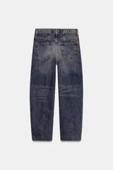 Jeans de tiro alto con corte barrel y diseño tapered, confeccionados en denim con efecto lavado y detalle de raya planchada. Presentan cintura con trabillas, cierre frontal con cremallera y botón, y bolsillos funcionales en delantero y espalda.