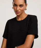 Blusa fucsia de manga corta con cuello redondo pespunteado, diseño sin estampa y efecto airflow con textura sutil. Cuenta con abertura trasera tipo gota y cierre con botón.