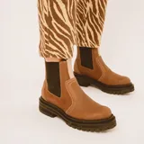 Botas estilo Chelsea de cuero color marrón, con paneles elásticos laterales negros, presillas traseras y suela chunky de goma negra con plataforma dentada.