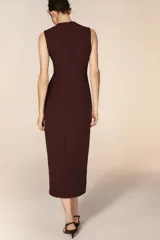 Vestido midi sin mangas de cuello redondo, con cierre frontal de botones dorados y cinturón integrado con hebilla metálica. Presenta bolsillos delanteros con solapa y una abertura en el bajo frontal.