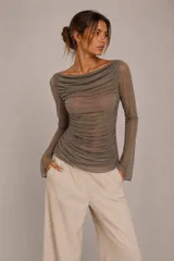Blusa de tul transparente color gris, con diseño drapeado en todo el cuerpo, escote bote y mangas largas.