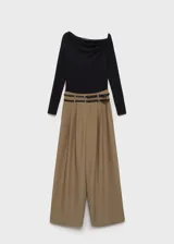 Mono de diseño combinado con cuerpo de remera negra de escote asimétrico y manga larga, unido a un pantalón de vestir color beige de corte recto con bolsillos laterales y cinturón doble integrado.