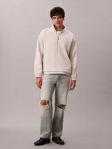 Buzo polar de Calvin Klein en color beige, con cuello alto tipo mock neck y cierre de media cremallera frontal. Presenta un diseño de corte regular con mangas largas, bajo ajustable con cordón y logo de la marca bordado en el pecho.