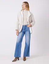 Cardigan beige con diseño de espiga, forrado en corderito sintético blanco. Presenta vivos en contraste color tostado en los bordes, cuello solapa y bolsillos tipo parche con solapa. Cierre frontal con botones carey.