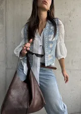 Chaleco de denim celeste con bordados detallados y apliques de brillos en la parte frontal.