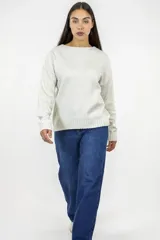 Buzo de punto color beige, con cuello redondo y diseño de corte recto. Presenta mangas largas con puños acanalados y ruedo también acanalado.
