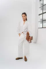 Pantalón de gabardina de algodón color blanco, con calce barrel, cintura media baja, bolsillos laterales y recortes frontales. Cuenta con cartera con botones semiocultos y detalle de ajuste en el ruedo con botones.