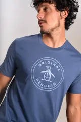 Remera de cuello redondo y manga corta, color azul, con estampado circular en el pecho que incluye el logo de la marca Original Penguin.