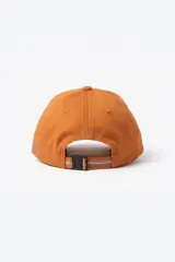 Gorra de lona color naranja con parche frontal bordado y la palabra Pastiche bordada en el lateral en color azul. Cuenta con diseño regulable en la parte posterior.